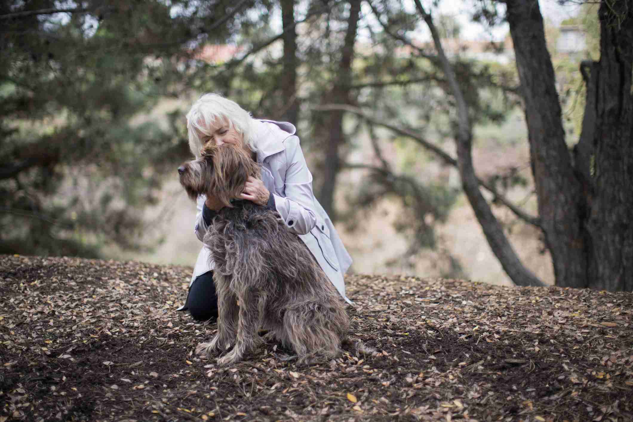 Senior woman hugging her dog outdoors