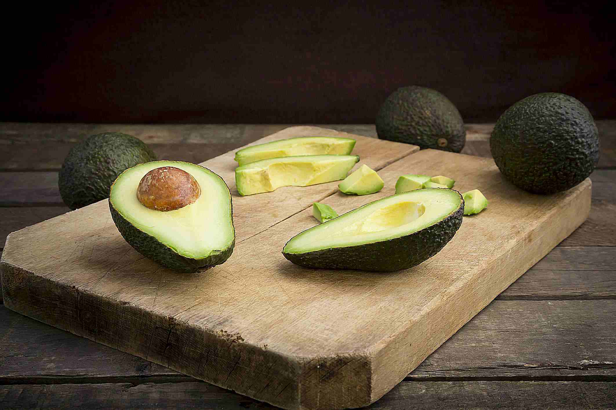 Full and cut up avocados on cutting board