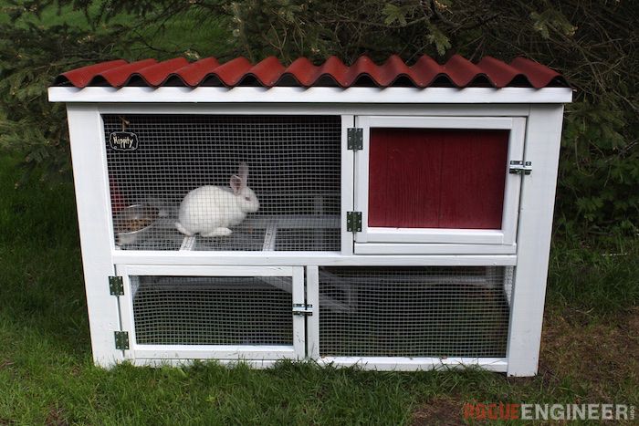 A red and white rabbit hutch with a red rabbit inside.