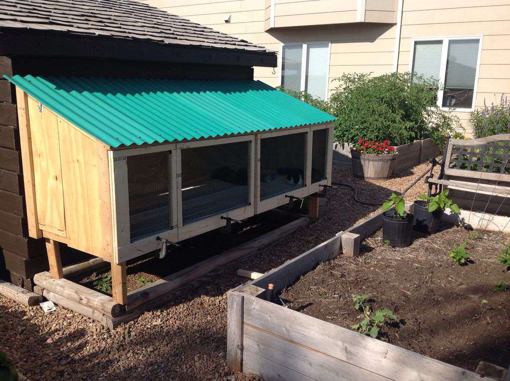 An outdoor rabbit hutch with teal roof.