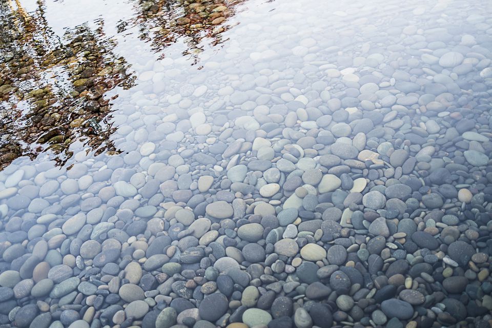 Pebbles on a river bed. Reflections and ripples on the surface.