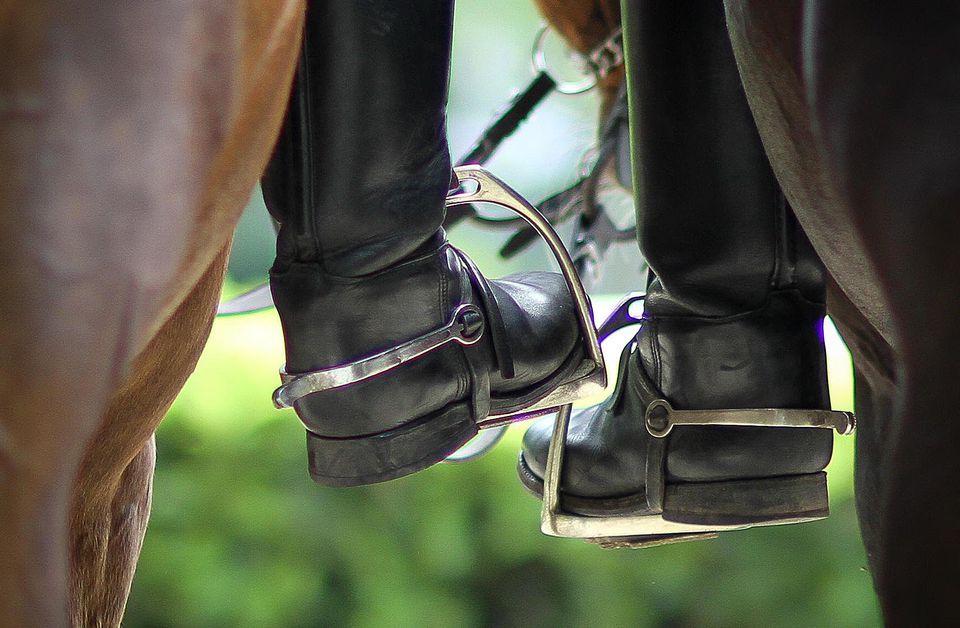Closeup of horseback riders' boots in stirrups
