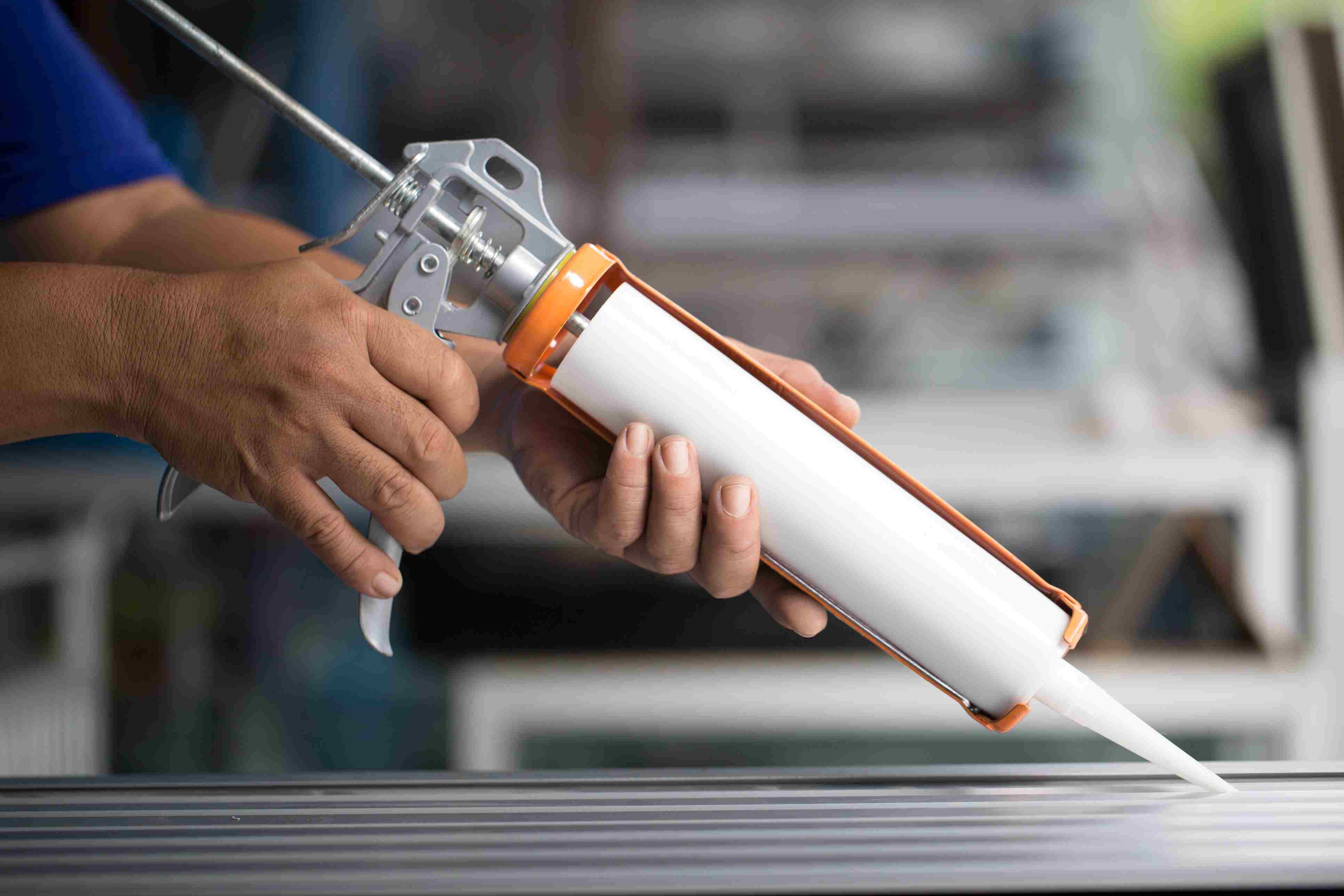 Person applying silicone through a tube.