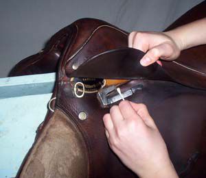 Person cleaning off soap on a leather saddle.