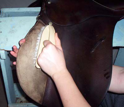 Person brushing suede or rough-out on a saddle.