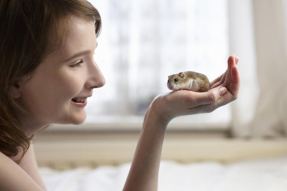Young woman holding hamster in hand.