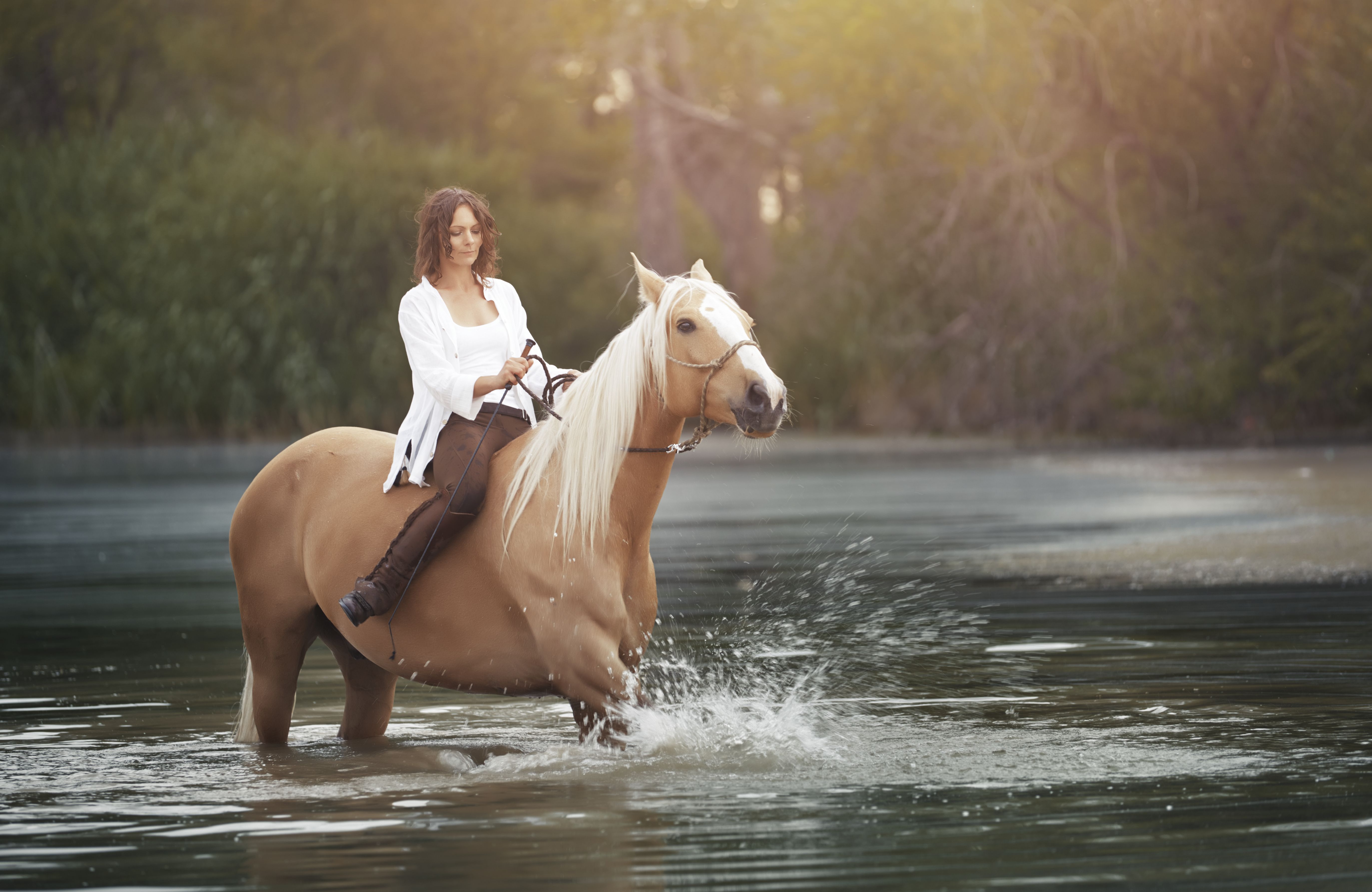 Woman riding on a horse through river